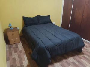 Casa amplia barrio privado Miramar في ميرامار: سرير لحاف ازرق وقفة ليلية