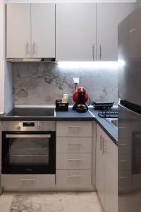 a kitchen with white cabinets and a stove top oven at Elario studio in Larisa
