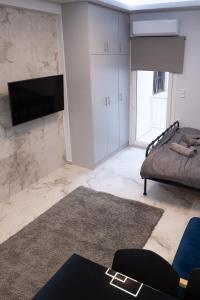 a living room with a bed and a television on a wall at Elario studio in Larisa