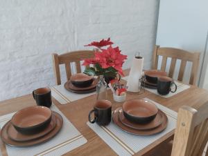 a table with plates and cups and a vase with flowers at Lugar tranquilo in Colonia del Sacramento