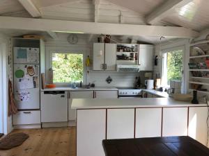 een keuken met witte kasten en witte apparaten bij Unique, Artistic House With Fjord View in Holbæk