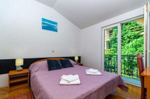 a bedroom with a bed with purple sheets and a window at Apartments Franka in Klek