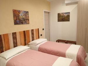 a hotel room with two beds and paintings on the wall at A casa di Aurora -Bed and breakfast in Caprie