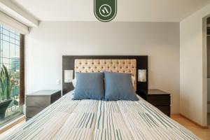 a bedroom with a large bed with two blue pillows at 2 BR Condo in Polanco with Pool and Gym in Mexico City