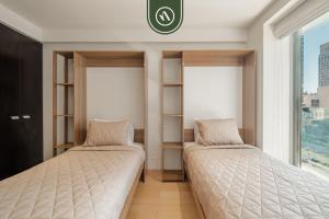 two beds in a room with windows at 2 BR Condo in Polanco with Pool and Gym in Mexico City