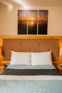 a bedroom with a bed with three paintings on the wall at Loft precioso con cocineta parking SmartTV in San Cristóbal de Las Casas