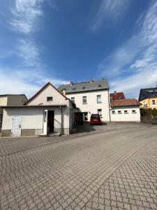 a white building with a car parked in a driveway at Landgasthof zur guten Quelle in Wermsdorf