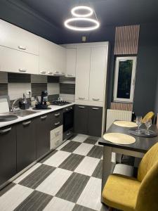 a kitchen with white cabinets and a table and a sink at Militari Residence Luxury 32 in Roşu