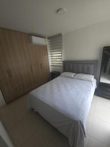a bedroom with a large white bed and wooden cabinets at Paz y Comodidad en Ricaurte, a 10 Min de Girardot in Ricaurte