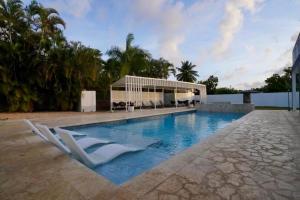 a swimming pool with two white chairs and a building at Beachtown Luxury Villas Apt 104 in Aguacate