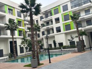 a building with palm trees in front of a pool at Cozy appartement luxueux in Mohammedia