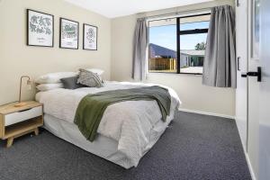 a white bedroom with a bed and a window at Pet friendly holiday home and spa in sunny Cromwell in Cromwell