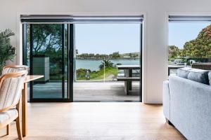 a living room with a door open to a patio at Okiwi Landing, Stylish, Central in Raglan