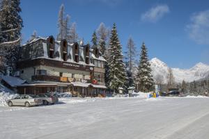 a large building with cars parked in the snow at Penzión Pleso in Vysoke Tatry - Strbske Pleso