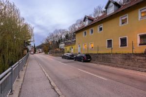 eine Straße mit zwei Autos neben einem gelben Gebäude in der Unterkunft COY Apartments Kaltenleutgeben - Nature Meets Style in Kaltenleutgeben