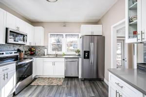 eine Küche mit weißen Schränken und einem Edelstahlkühlschrank in der Unterkunft Soak n Stroll 2 State St Casino Firepit Dogs OK in Bristol + 10 Fotos