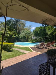 vista sulla piscina con sedie e ombrellone di Chácara Rosa Cortiana a São Gabriel