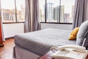 a hotel room with a bed and a phone at Elegance Hotel in La Paz