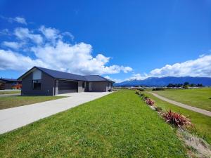 una casa en un campo de hierba junto a una acera en Mountain View Getaway, en Te Anau