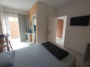 una camera da letto con un letto e una televisione a parete di kitnet & Suítes Aloha Beach Bertioga a Bertioga Altre 6 foto