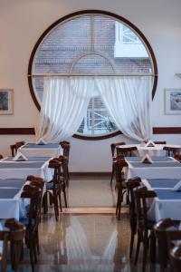 a room with tables and chairs and a large window at Hotel Reviens in Pinamar