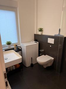 a bathroom with a white toilet and a sink at Modernes 1 Zimmerapartment nahe Frankfurt am Main in Heusenstamm