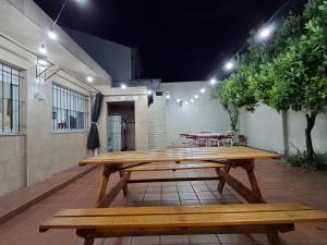 a wooden picnic table on a patio with two benches at CASA DEL NARANJO in Rosario