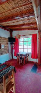 Habitación con cortinas rojas, mesa y TV. en Mamacoca, en Purmamarca