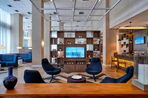 a lobby with chairs and a television in a building at Courtyard by Marriott Rio de Janeiro Barra da Tijuca in Rio de Janeiro