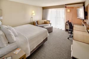 a hotel room with a bed and a television at Courtyard St. Louis Airport/Earth City in Bridgeton