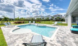 a swimming pool with two chairs and a bench at Serene Vibrant 4 Bdrm Villa with Games Room at Encore in Orlando