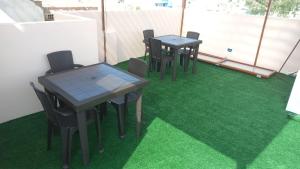 a group of tables and chairs on a green floor at CARDOS HOSTAL in Pisco