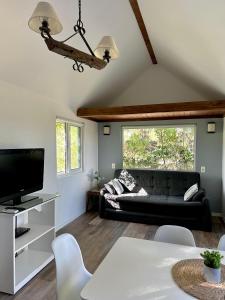 a living room with a black couch and a tv at Tiny House Mercedes in Mercedes