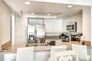 a kitchen with white cabinets and a stainless steel refrigerator at Waterfront Condo with Dock Access in Carlsbad! in Carlsbad
