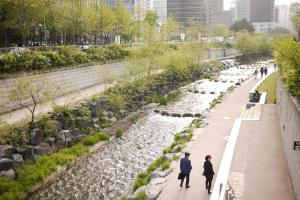 a man and woman walking down a sidewalk next to a river at Fully Mini Hotel in Seoul