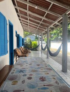 een veranda met een hangmat, stoelen en een vloerkleed bij casa de praia em Itapoá SC a uma quadra da praia in Itapoa