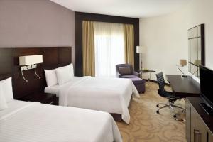 a hotel room with two beds and a desk at Courtyard by Marriott Riyadh Diplomatic Quarter in Riyadh