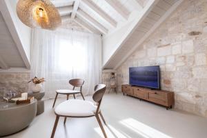a living room with a tv and a stone wall at Forkira Luxury Hvar in Hvar