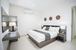 una camera da letto bianca con un letto grande e una scrivania di Harmony Beach Suite a Seminyak