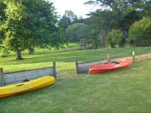 two kayaks are parked on the grass next to a fence at At Parkland Place B&B in Whitianga