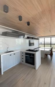 a kitchen with white cabinets and a wooden ceiling at Loft luxo p/ 4 pessoas, a 50m do mar in Ilha da Restinga