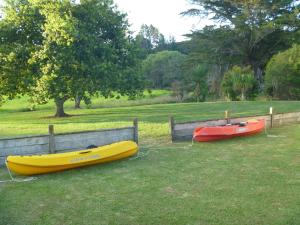 two kayaks are parked on the grass next to a fence at At Parkland Place B&B in Whitianga