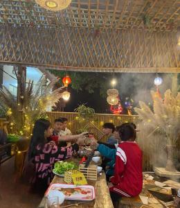 un grupo de personas sentadas en una mesa con comida en Hang Mua Bungalow, en Ninh Binh