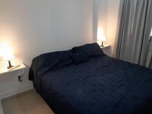 a bedroom with a black bed with two lamps at Abuela Betty in Villa Carlos Paz