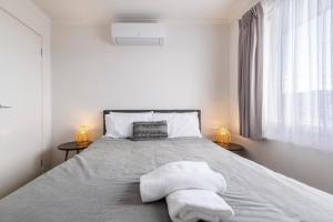 a white bedroom with a bed with two lamps at Ocean Vista in Lakes Entrance