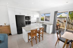 una cucina con mobili bianchi, tavolo e sedie di Sea Breeze a Paynesville
