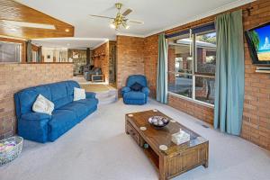Una sala de estar con un sofá azul y una mesa. en Fern Rest, en Lakes Entrance