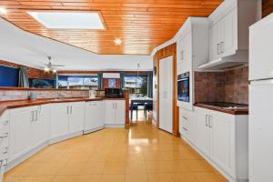 cocina con armarios blancos y techo de madera en Fern Rest, en Lakes Entrance