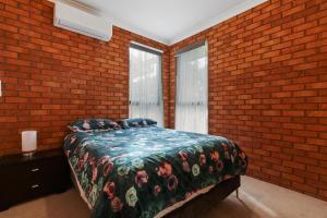 Un dormitorio con una cama y una pared de ladrillo. en Fern Rest, en Lakes Entrance
