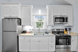 a white kitchen with white cabinets and a sink at Appian Way Maltese Cottage in Fredericksburg